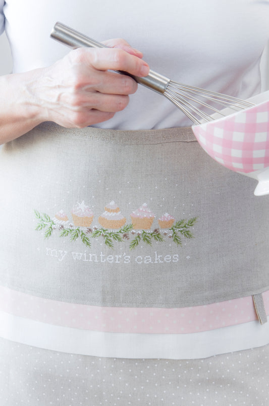 Grille de broderie point de croix : tablier My Winter’s Cakes, motifs cupcakes gourmands. 163 x 81 pts, imprimé couleur (Réf. DMC) sur 6 pages. Illustration J. Lentini.