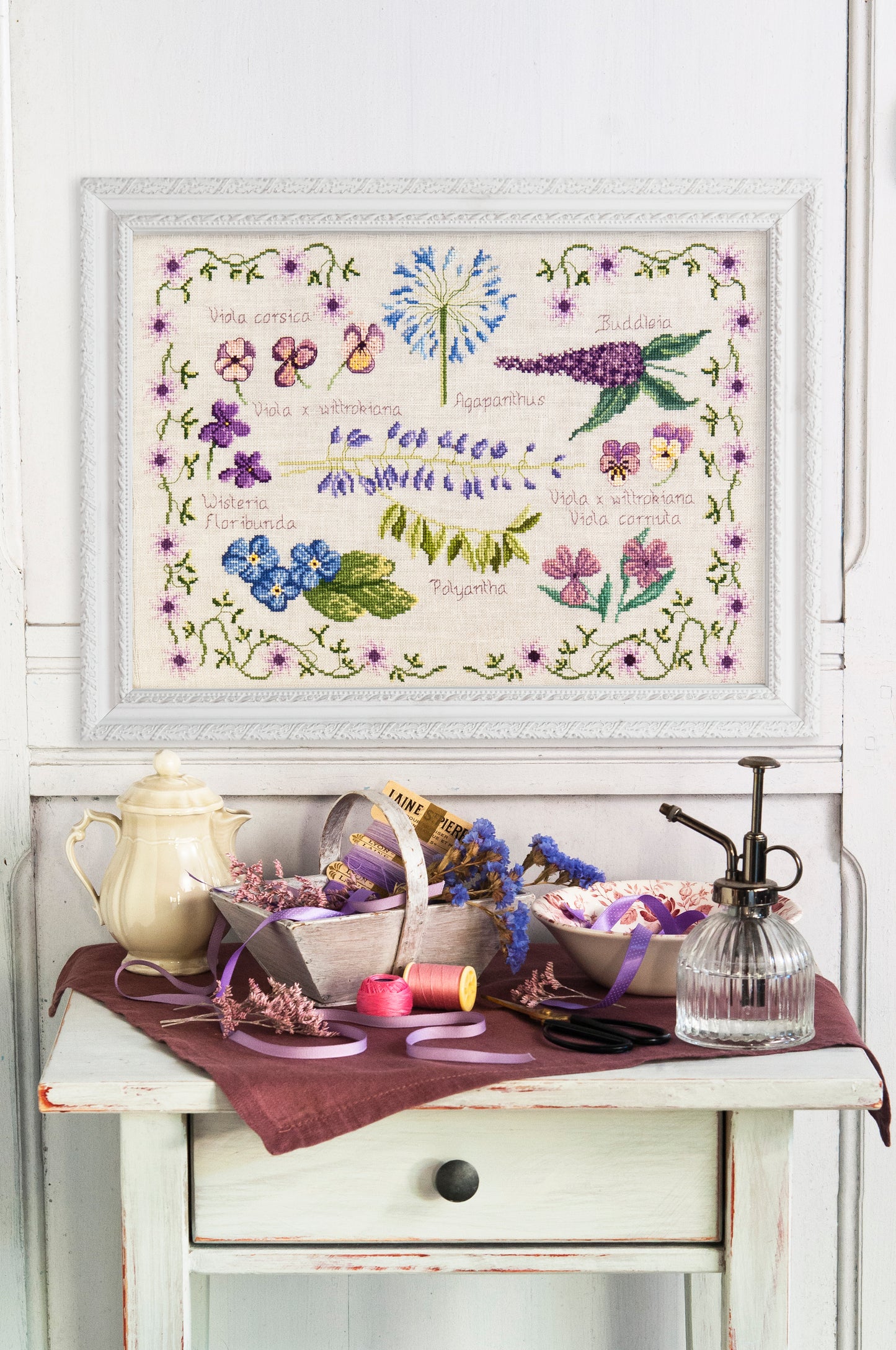 Grille point de croix – Abécédaire fleurs mauves : pensées, agapanthes, glycines et fleurs mauves avec leurs noms, encadrées d'une guirlande fleurie, inspiré des planches botaniques – Création Point de Croix