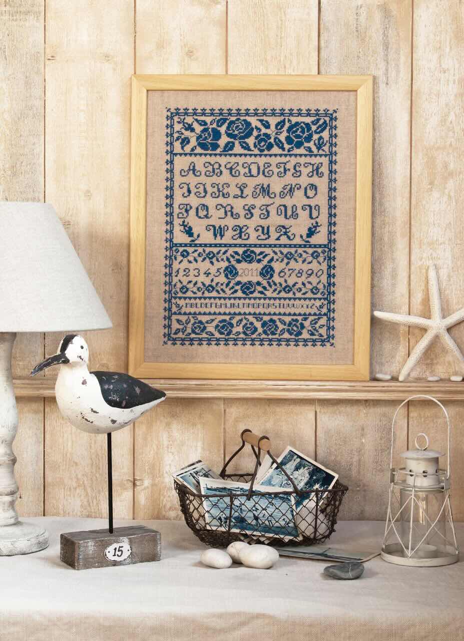 Grille point de croix – Abécédaire roses bleues : alphabet entouré de roses bleues délicatement disposées sur toile de lin DMC, style romantique et intemporel – DMC & Création Point de Croi