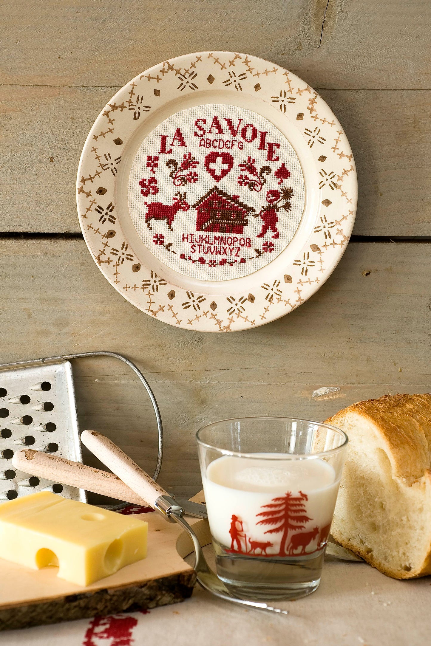 Grille broderie point de croix : assiette savoyarde avec ramoneur, chalet et croix. Motif 72x73 pts, env. 13x13 cm sur Aïda 7 pts ou lin 11 fils. Ref. DMC.