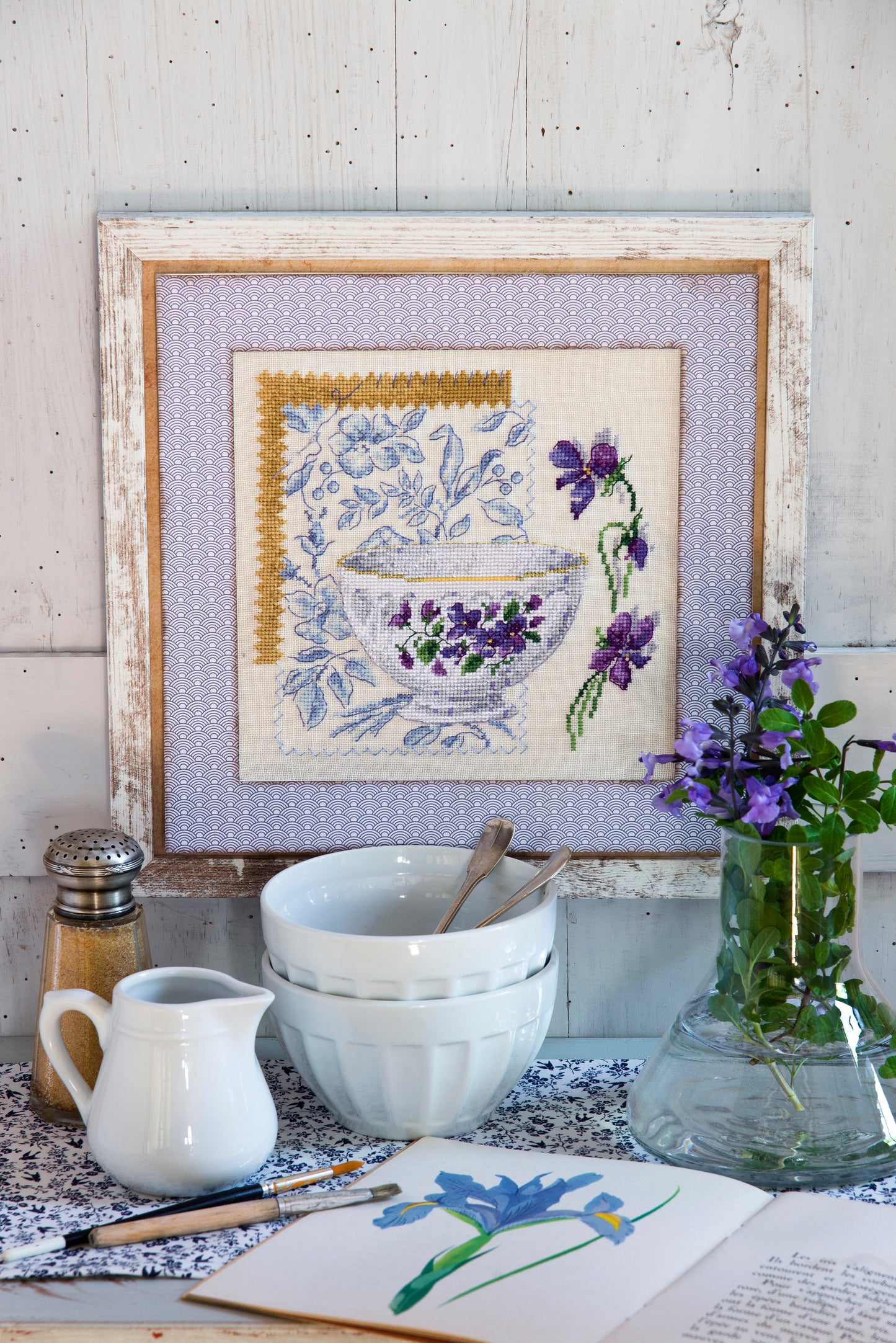 Grille point de croix – Bol violettes : bol en porcelaine blanche orné de violettes mauves et violettes sur fond de tissu fleuri bleu, ambiance romantique et printanière – Création Point de Croix"