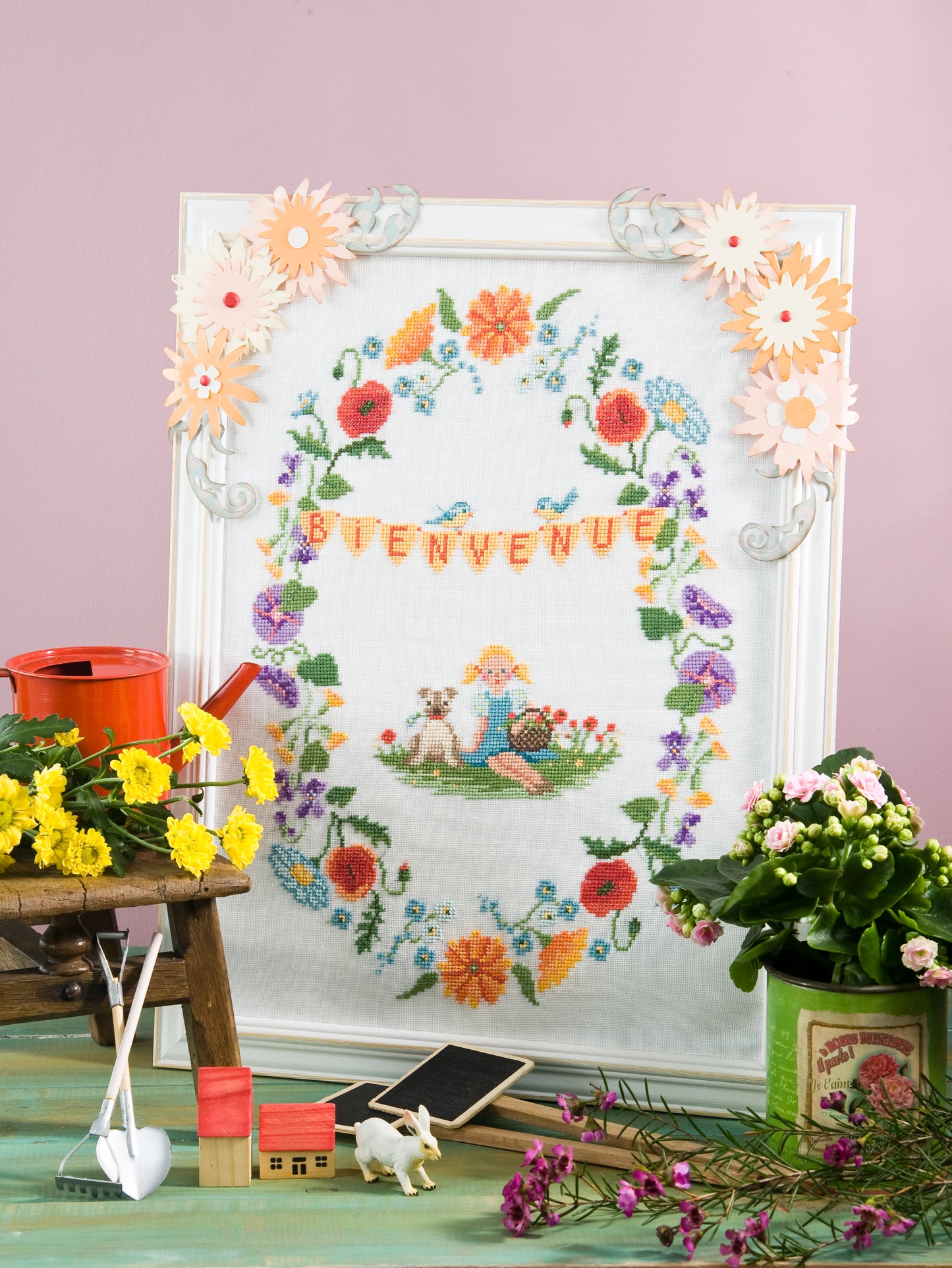 Grille de broderie point de croix : cadre Bienvenue couronne de fleurs de printemps. Motif 140 x 200 pts, imprimé couleur (Réf. DMC) sur 4 pages. Illustration Aurelle