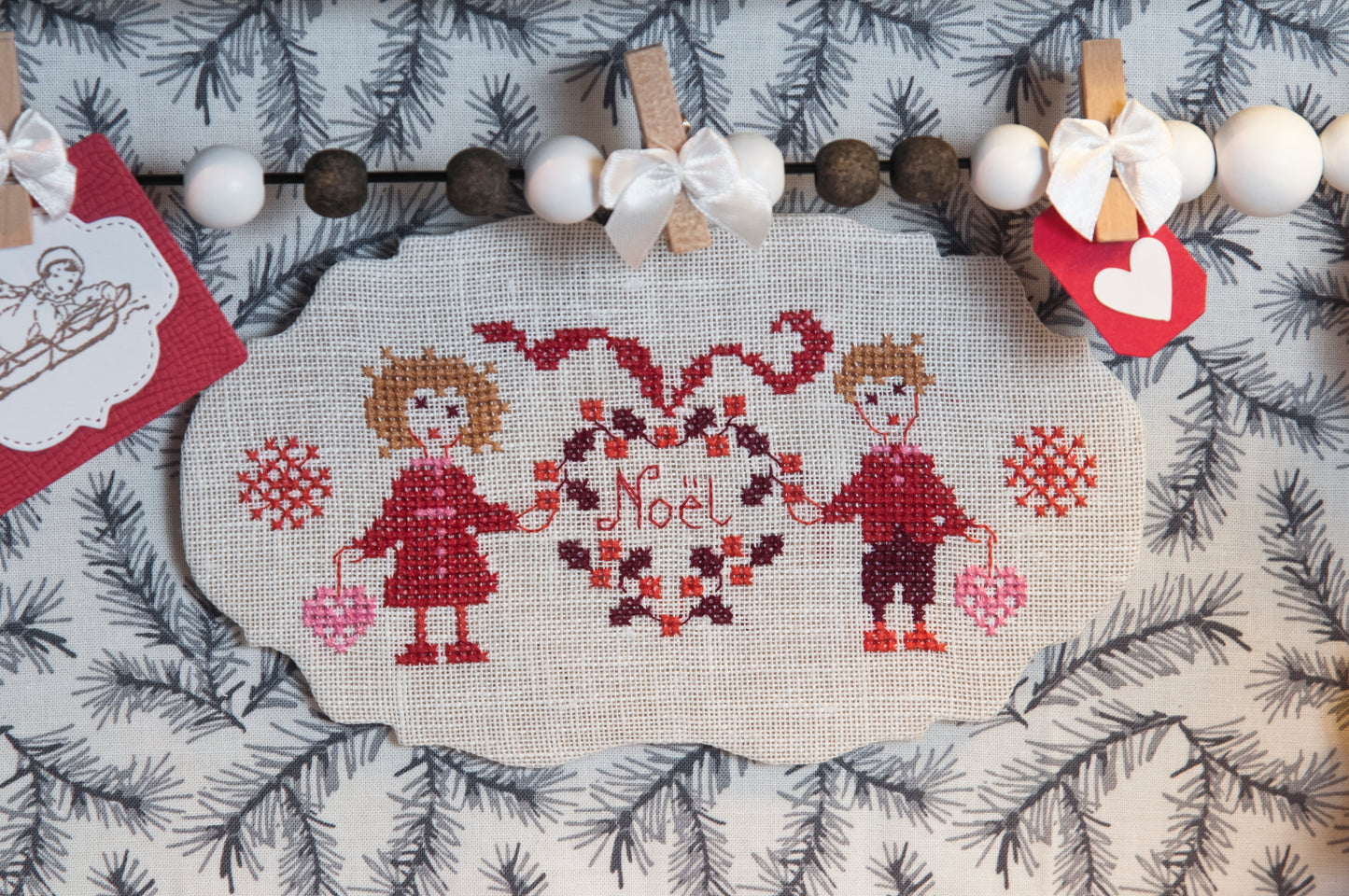Grille de broderie point de croix : petits cadeaux de Noël (guirlande, musiciens, faons, flocons). Imprimé couleur (Réf. DMC) sur 6 pages. Illustration P. Samouiloff.