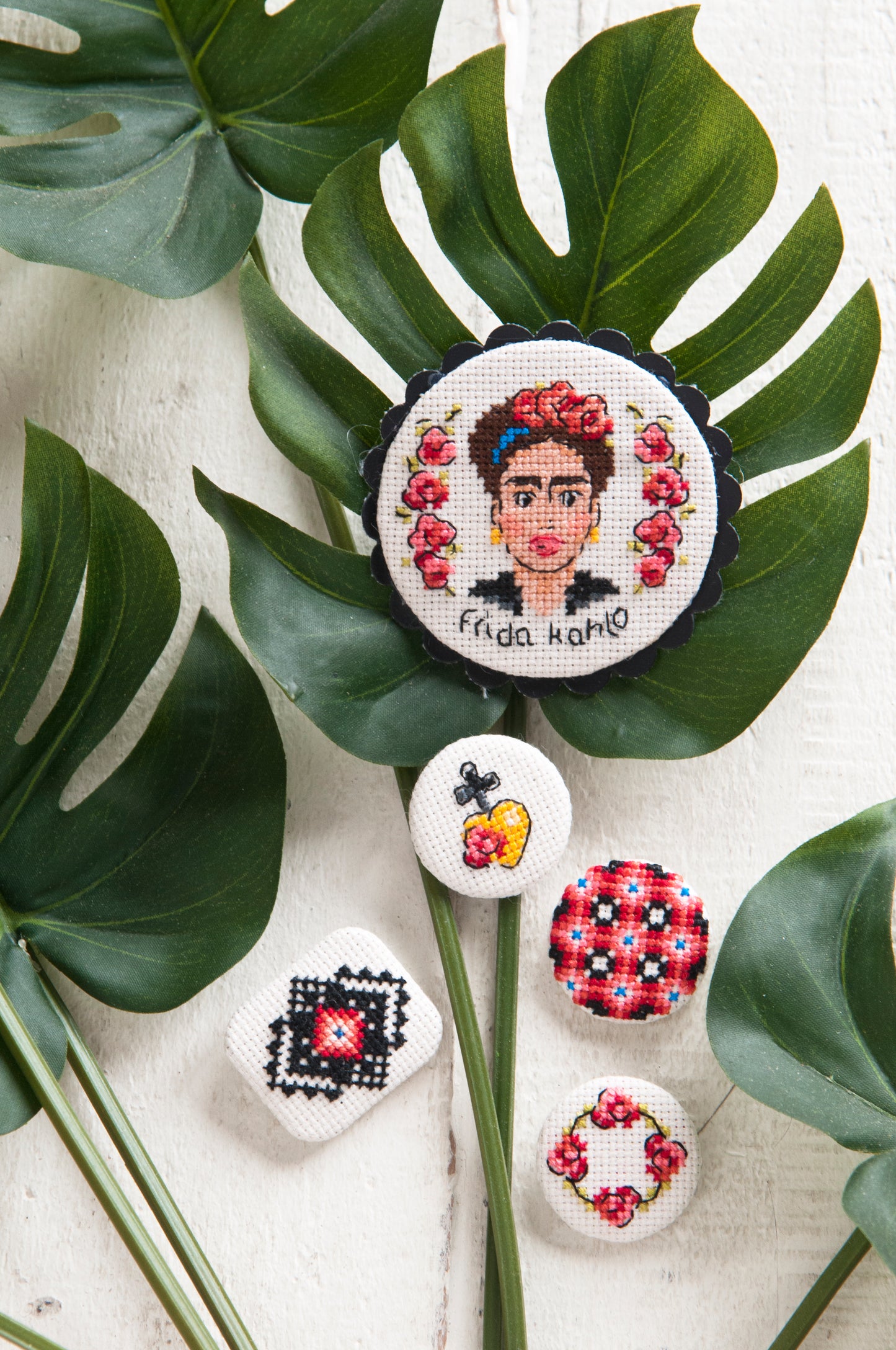 Grille point de croix : 5 broches brodées (Frida Kahlo, roses, cœur…). Imprimée sur 4 pages avec symboles et couleurs DMC. Aïda 5,5 points blanc.