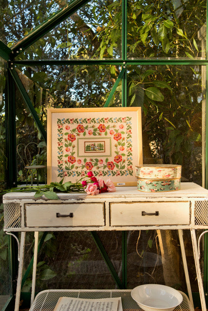 Composition florale romantique brodée sur lin naturel : roses, boutons et frises végétales en rose poudré et rouge profond. Motif 32,7 × 25,4 cm, esprit jardin ancien.