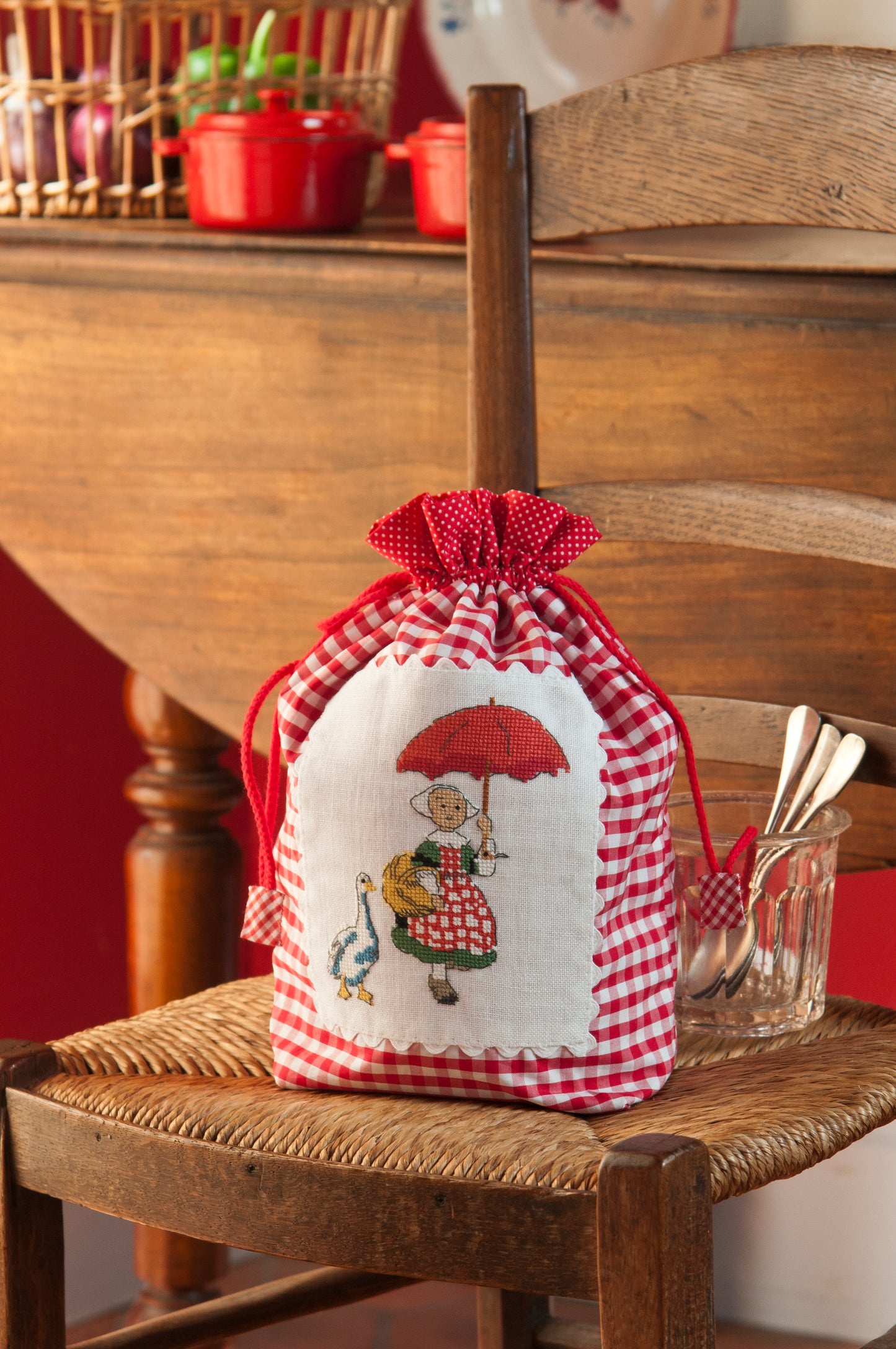 Grille broderie point de croix : pochon Bécassine en vichy rouge, motif 63×78 pts, 11,5×14,2 cm. Symboles + couleurs DMC, 6 pages.