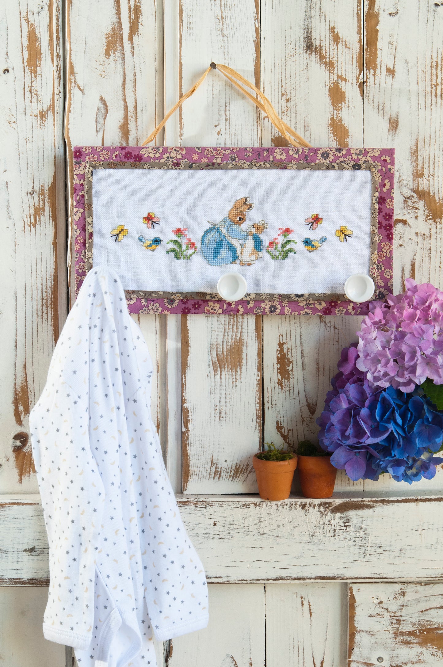 Grille point de croix : frise porte-manteaux Pierrot-Lapin sur lin blanc DMC. Motif 114 × 34 pts, env. 20,7 × 6,2 cm. Imprimé symboles & couleurs, 6 pages.