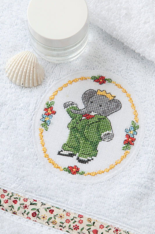 Grille broderie point de croix : médaillon Babar pour serviette de bain, motif 49×59 pts, 9×11 cm. Symboles + couleurs DMC, 6 pages.