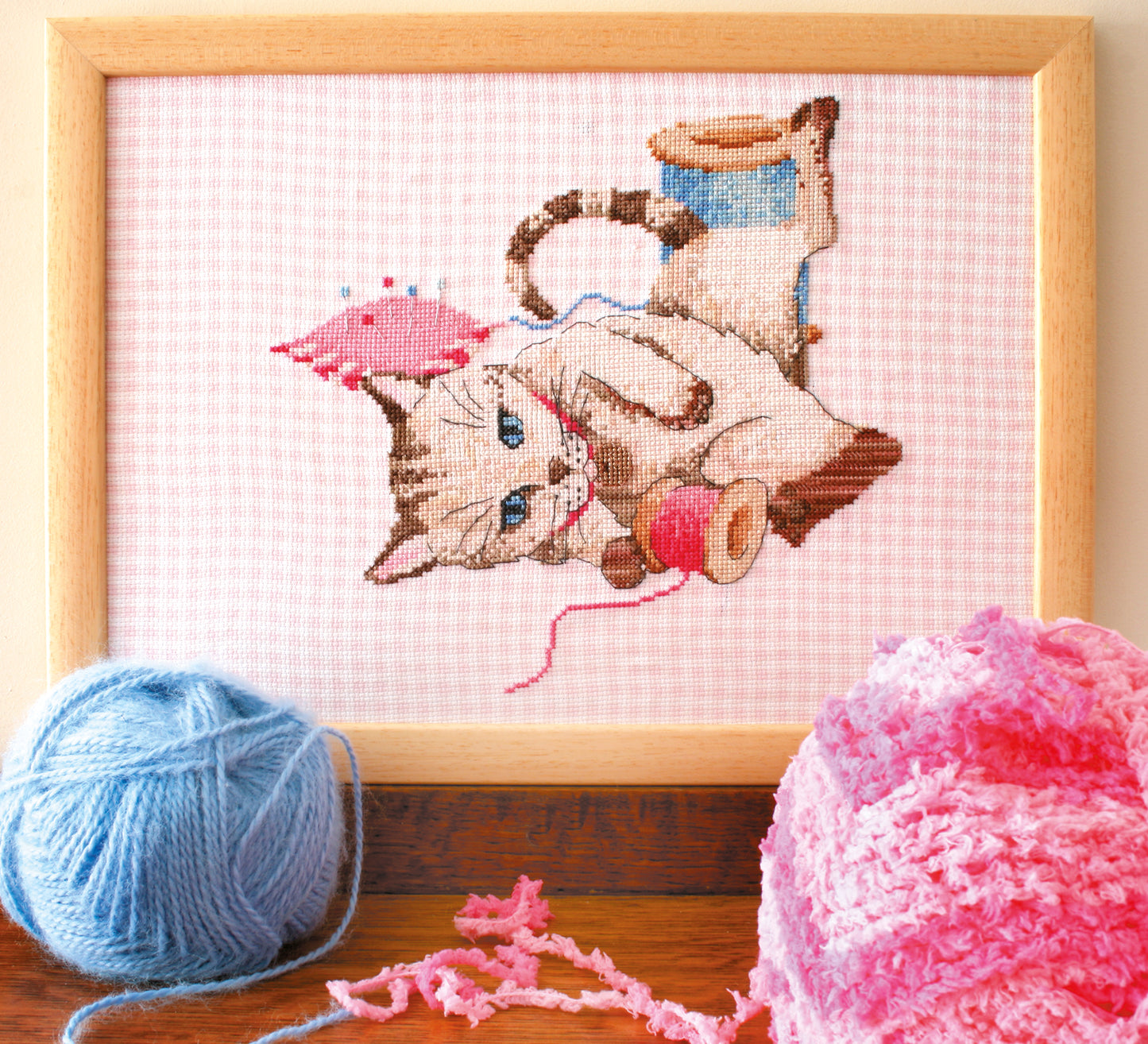 Grille point de croix : chaton joueur parmi les pelotes et accessoires de couture. Motif 120×123 pts, environ 21,8×22,4 cm. Douceur et malice.