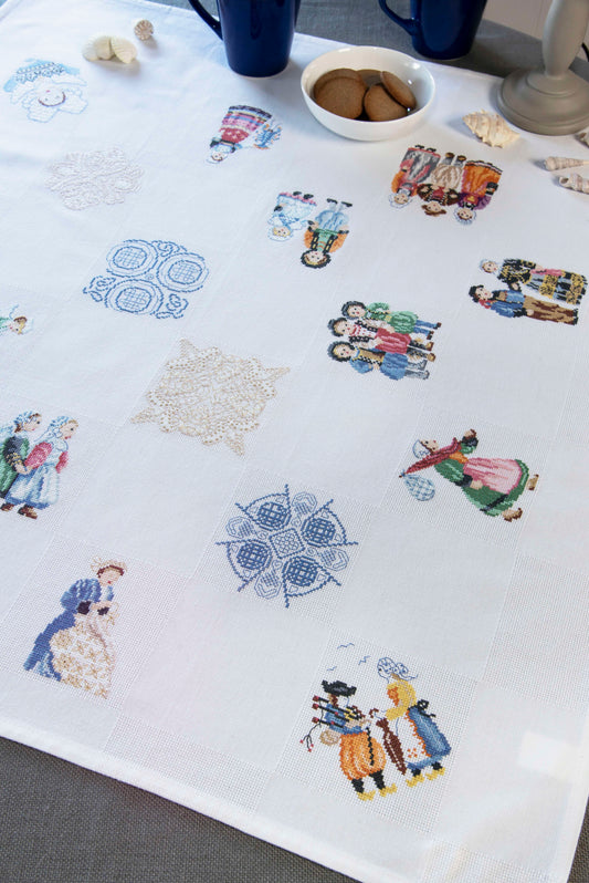 Grille de broderie point de croix « Nappe Bretagne » par M. Bonnin : personnages en costume breton et bigoudènes sur toile blanche 5,5 pts. DMC, 6 pages, motif 11 x 11 cm.