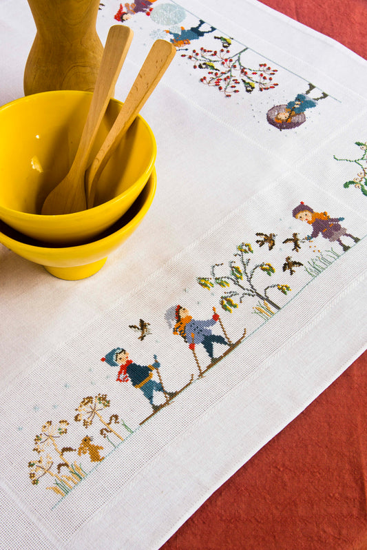 Grille de broderie point de croix : nappe hiver avec scènes enneigées par P. Samouiloff. Réf. DMC incluse. À broder sur Aïda ou lin. Création Point de Croix.