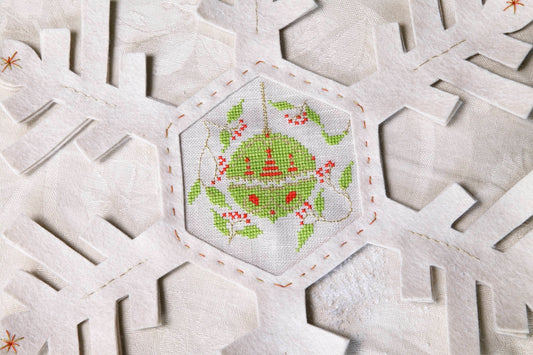 Grille de broderie point de croix : napperon de neige, motifs boule de Noël et sapin sur 4 pages. Symboles et couleurs DMC, sur lin blanc.