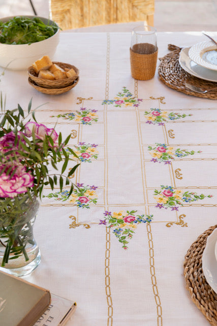 Grille de broderie point de croix « Nappes fleuries » : motifs fleuris et chaînes dorées à broder sur nappe lin blanc 11 fils. DMC, 8 pages.