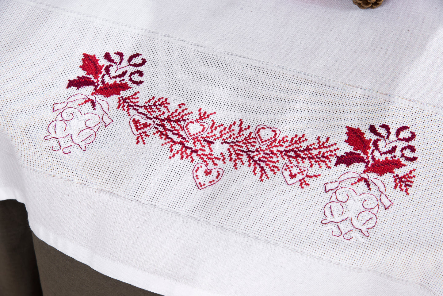Grille point de croix – Noël sur votre table, détail rouge : motif branche de Noël et cœur brodés en rouge sur nappe encadrée, décoration de table festive raffinée – Véronique Enginger & Création Point de Croix