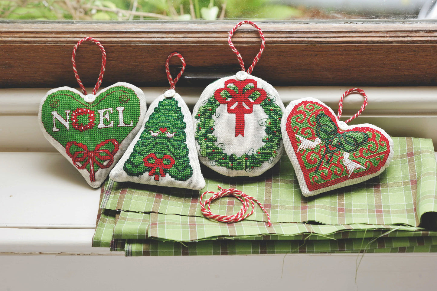 Grille broderie point de croix : ornements de Noël (cœurs, sapin, couronne). Environ 8-10 cm par motif, imprimée en couleur sur 4 pages. Réf. DMC incluses.
