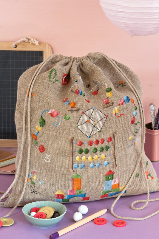 Grille de broderie point de croix « Sac à dos et trousse » par M. Bonnin : accessoires scolaires à broder sur lin bis 11 fils. DMC, 6 pages, sac 27 x 30 cm, trousse 5 x 22 cm.