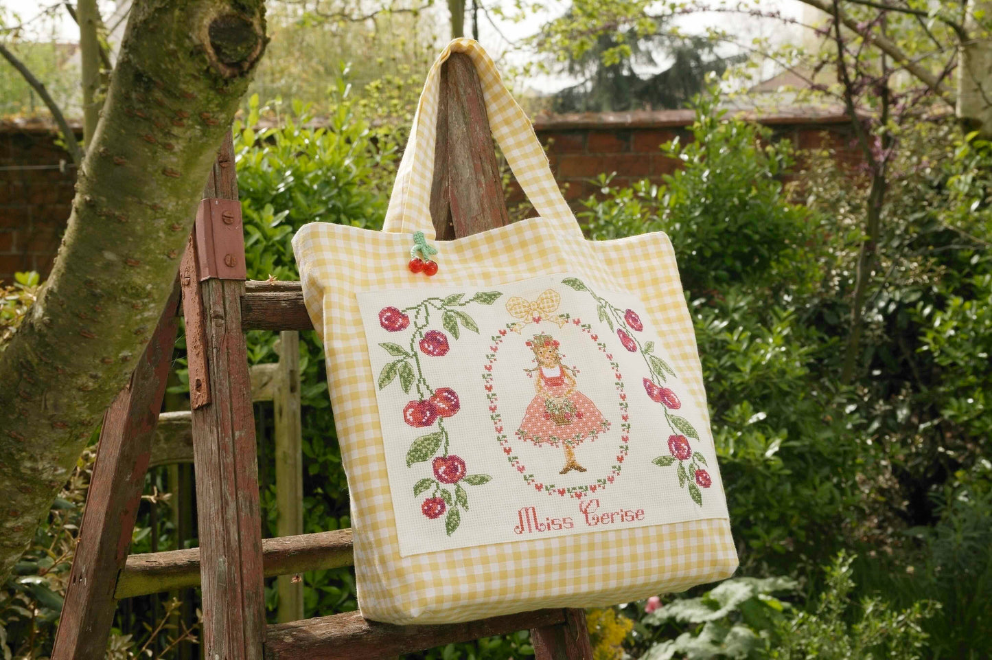Grille de point de croix Sac Miss Cerisette : cerises et Vichy jaune sur Aïda 5,5 pts. 110 x 150 points. Références DMC sur 4 pages.
