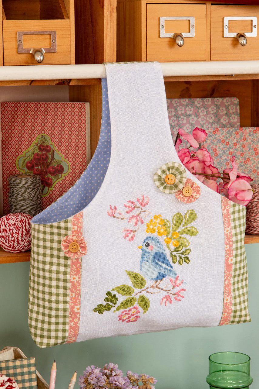 Grille broderie point de croix : sac à ouvrage avec oiseau sur branche fleurie. 90 x 105 pts, imprimée sur 4 pages. Réf. DMC incluses.