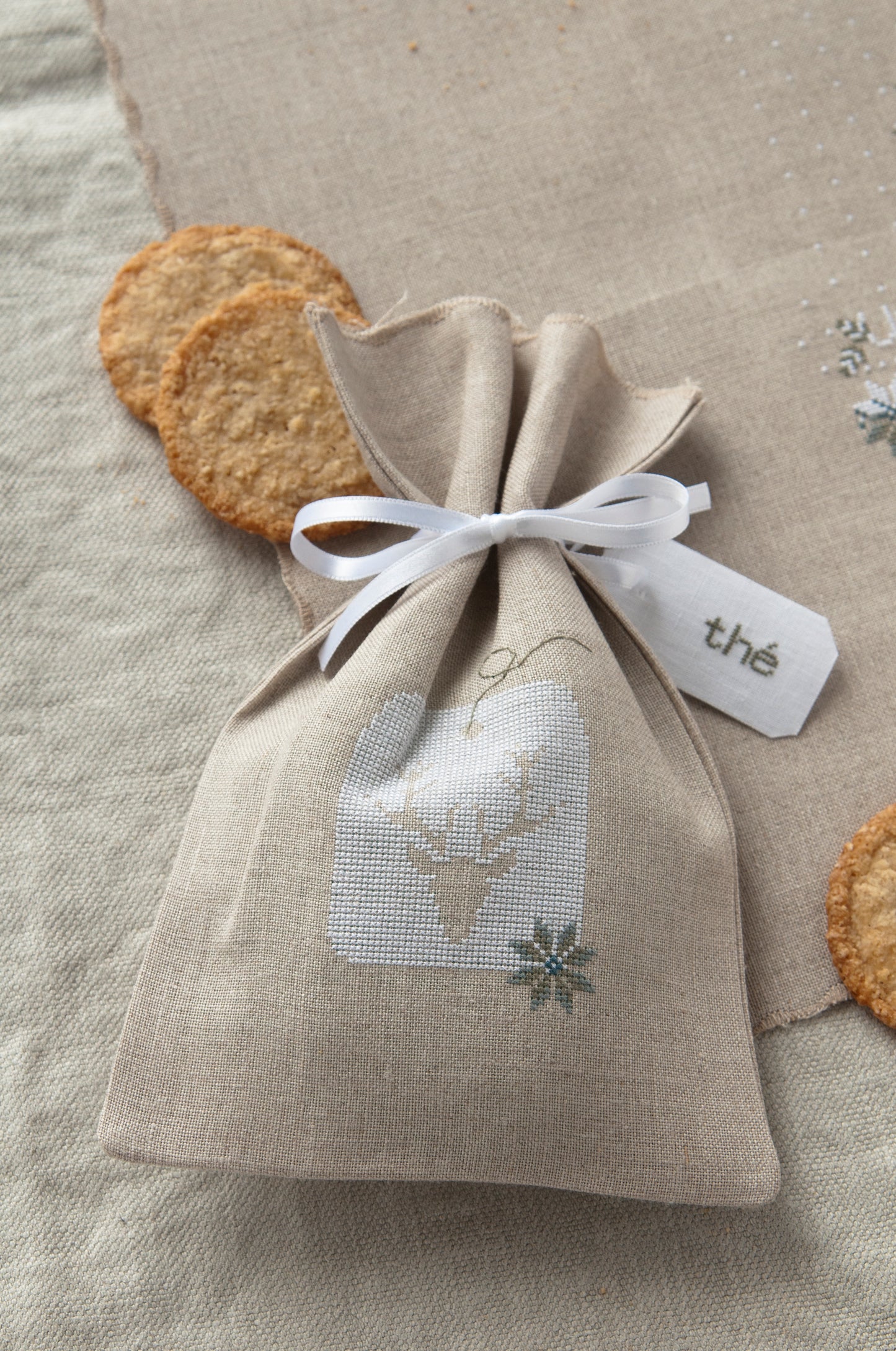Grille de broderie point de croix « Sachet de thé et set de table » par J. Lentini : flocons de neige sur lin 14 fils. DMC, 6 pages – sachet et set assortis.