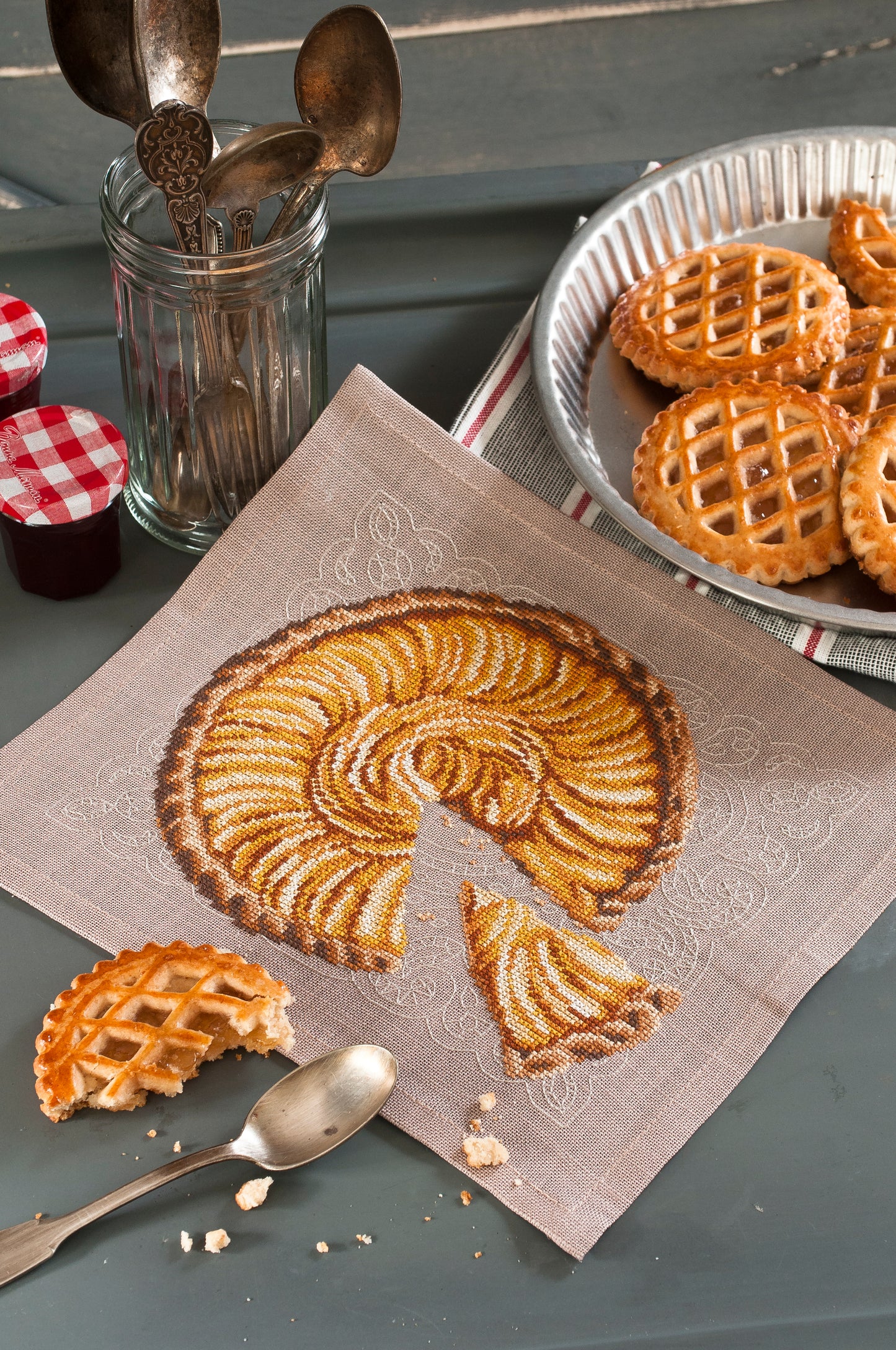Grille point de croix – Tarte gourmande : tarte aux pommes dorée sur fond de papier dentelle brodée sur toile de lin sépia 12 fils/cm, hommage à la pâtisserie traditionnelle française – Monique Bonin & Création Point de Croix