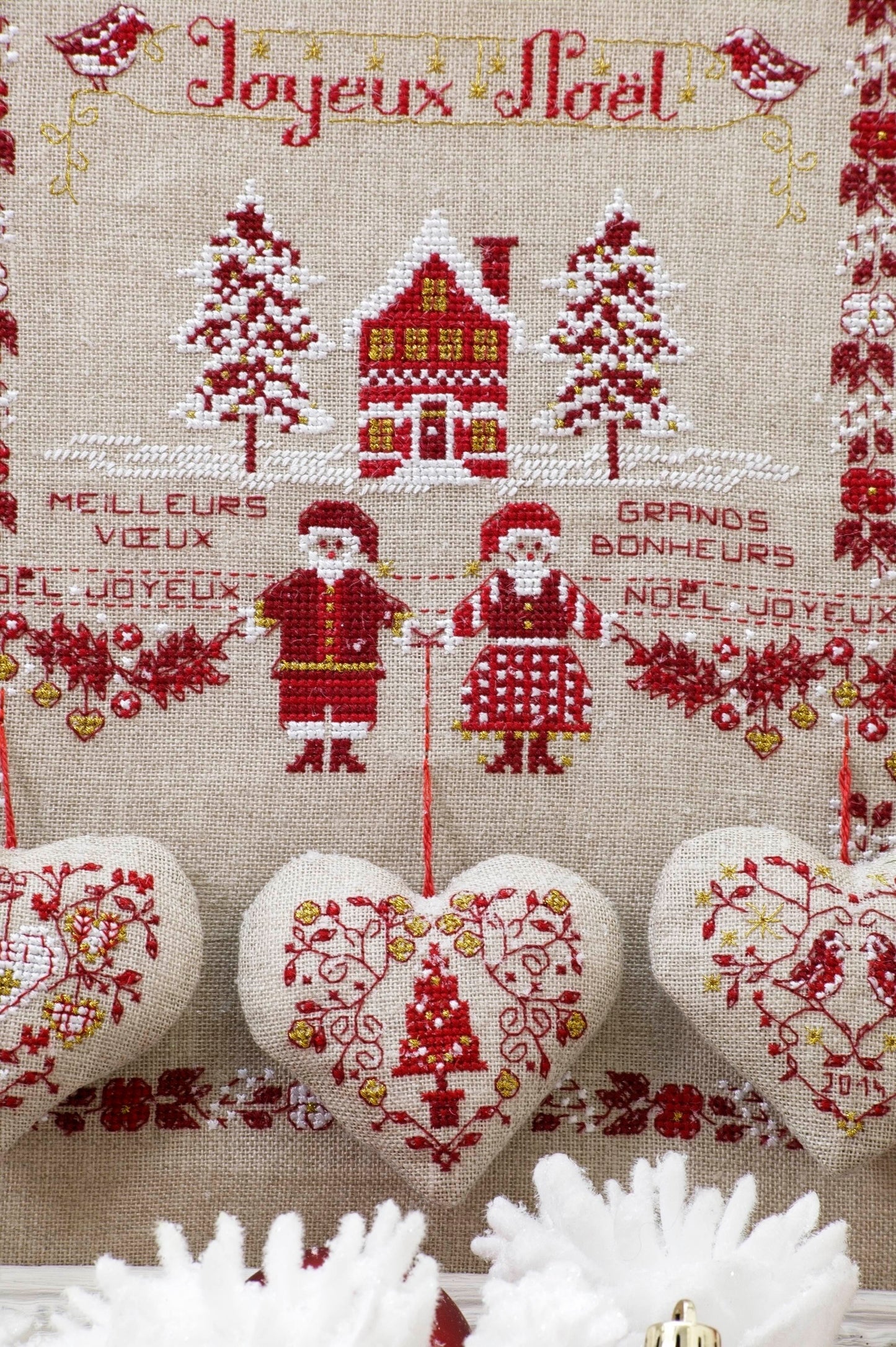 Grille de point de croix Un amour de Noël : sapins et cœurs sur lin bis. Motif 146 x 150 points. Références DMC sur 4 pages.