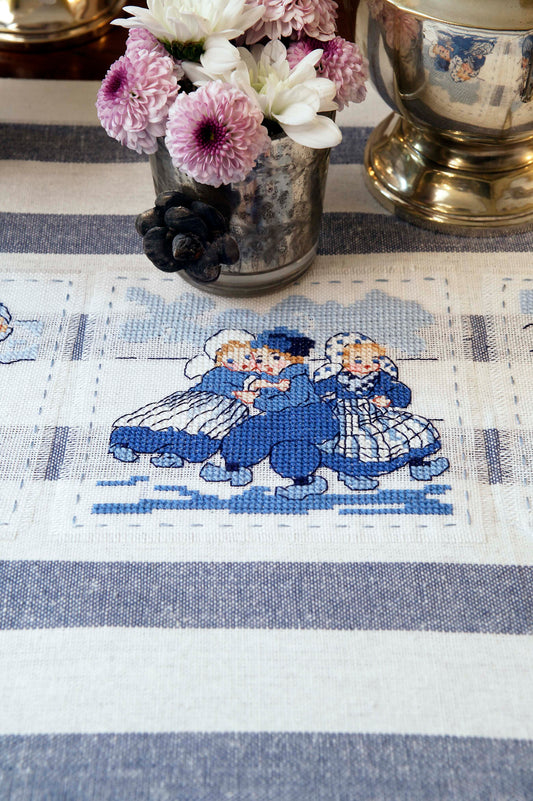Grille broderie point de croix : napperon style hollandais avec saynètes enfantines. 55 x 55 pts, imprimée en couleur sur 4 pages. Réf. DMC incluses.