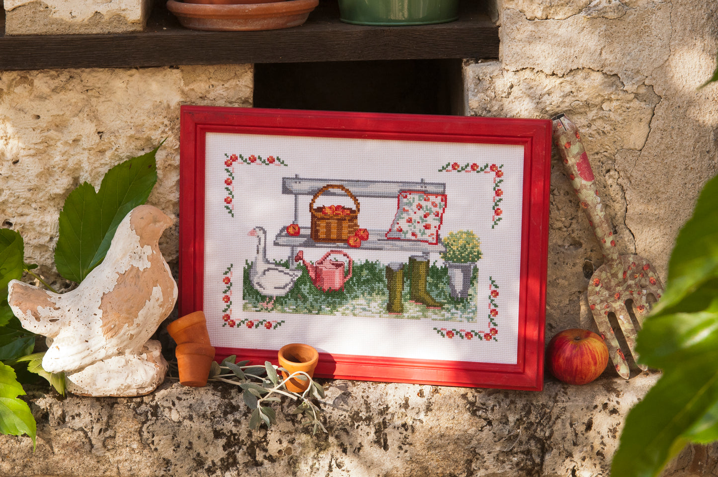 Grille point de croix – Après-midi enchanté au jardin : oie blanche, banc, panier de fruits et arrosoir rose, encadrée de frises fleuries – Création Point de Croix