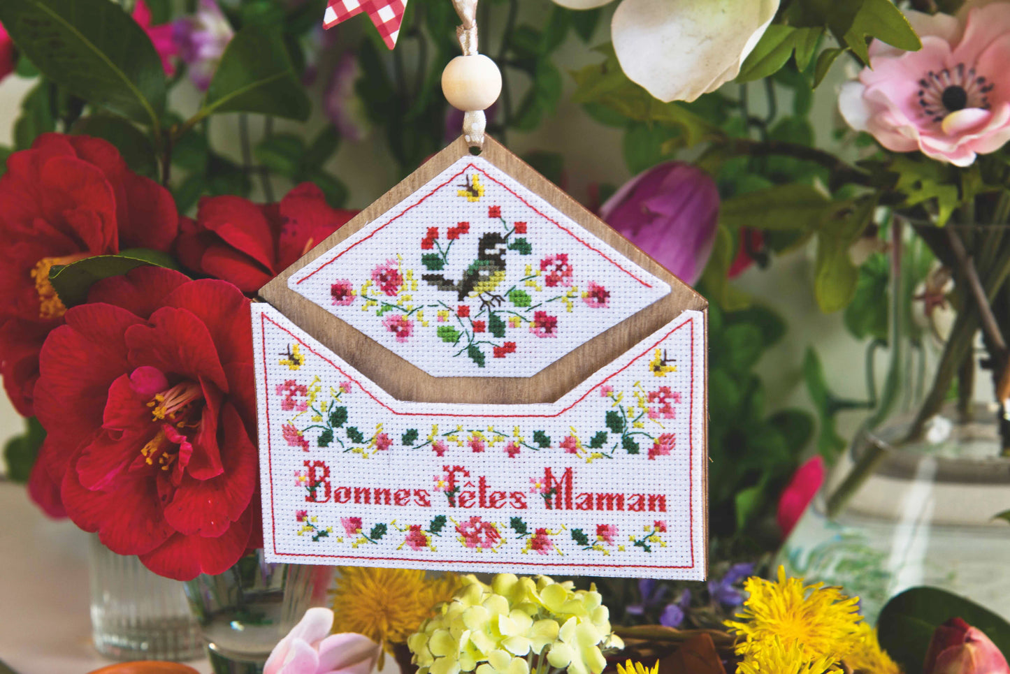 Grille point de croix : panneau enveloppe fleurie « Bonnes Fêtes Maman ». 79×70 pts, Aïda 7 pts/cm ou lin 14 fils/cm. 6 pages couleur, réf. DMC.