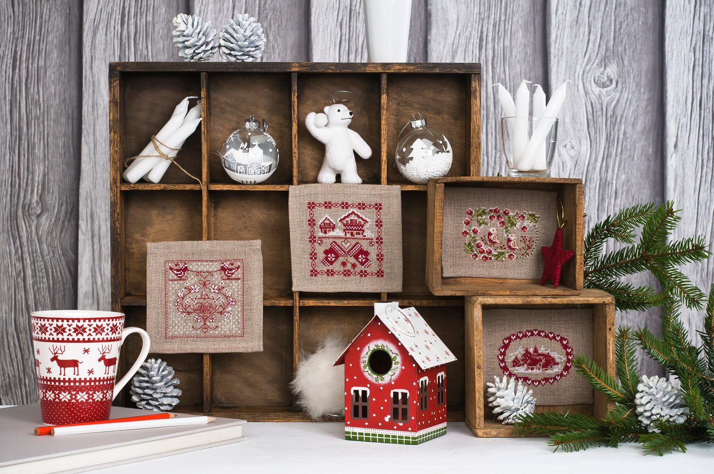Petits motifs hivernaux brodés sur toile Aïda naturelle, signés M.A. Réthoret-Melin. Chalets, oiseaux et cœurs nordiques en rouge et blanc, esprit montagne et Noël.