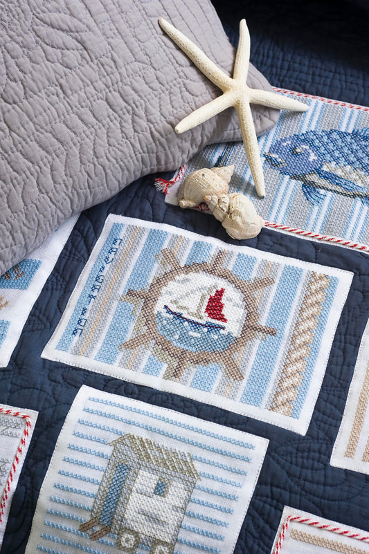 Grille point de croix Mon Plaid Marin par Création Point de Croix. Dégradés de bleus, coton perlé DMC, 6 pages. Motifs marins : poisson, épuisette, coquillage.