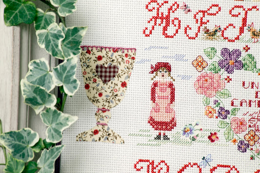 Grille broderie point de croix : ABC champêtre avec appliqués tissu fleuri. 125 x 124 pts, imprimée en couleur sur 4 pages. Réf. DMC incluses.