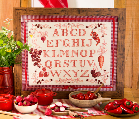 Grille point de croix – Abécédaire Légumes : alphabet traditionnel entouré de carottes, radis, cerises et framboises brodés en monochrome rouge, inspiré des marquoirs de cuisine anciens – Création Point de Croix
