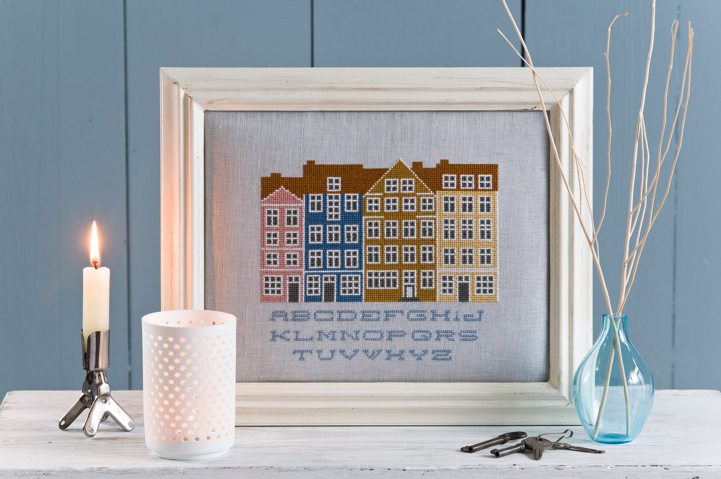 Sampler graphique inspiré des façades colorées de Copenhague, signé M.A. Réthoret-Melin. Brodé sur lin gris perle 12 fils/cm, esprit scandinave épuré, 20 × 16,5 cm.