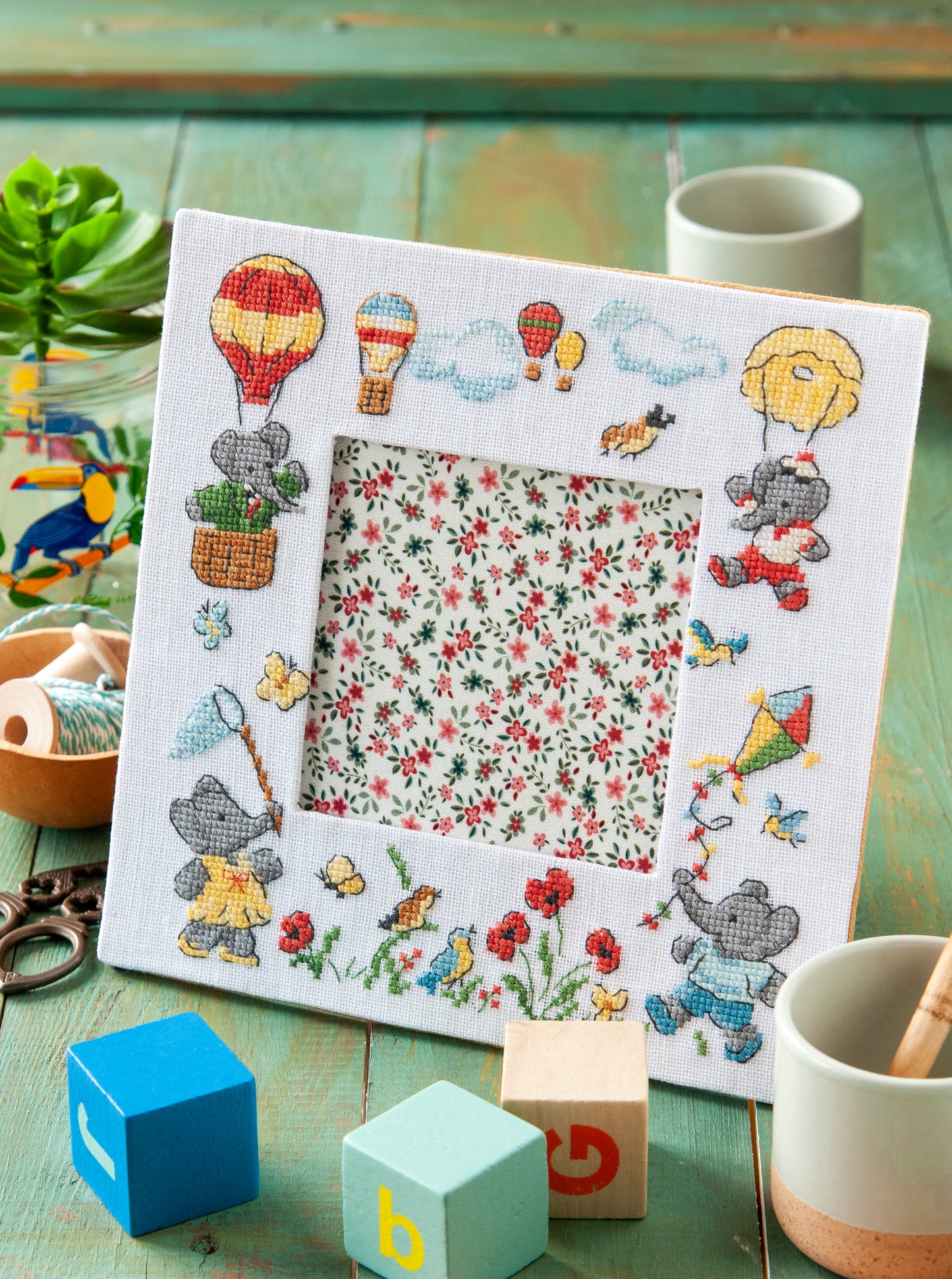 Grille broderie point de croix : cadre photo Babar, motif 100×100 pts, 18×18 cm, fenêtre 10×10 cm. Symboles + couleurs DMC, 6 pages.