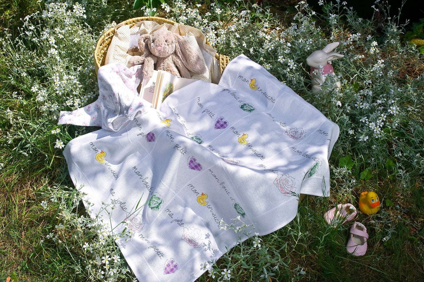 Grille broderie point de croix : plaid bébé avec frises chou, rose, cœur et canard. Motifs sur laid bébé blanc. Sur Aïda 5,5 pts ou lin 11 fils. Ref. DMC.