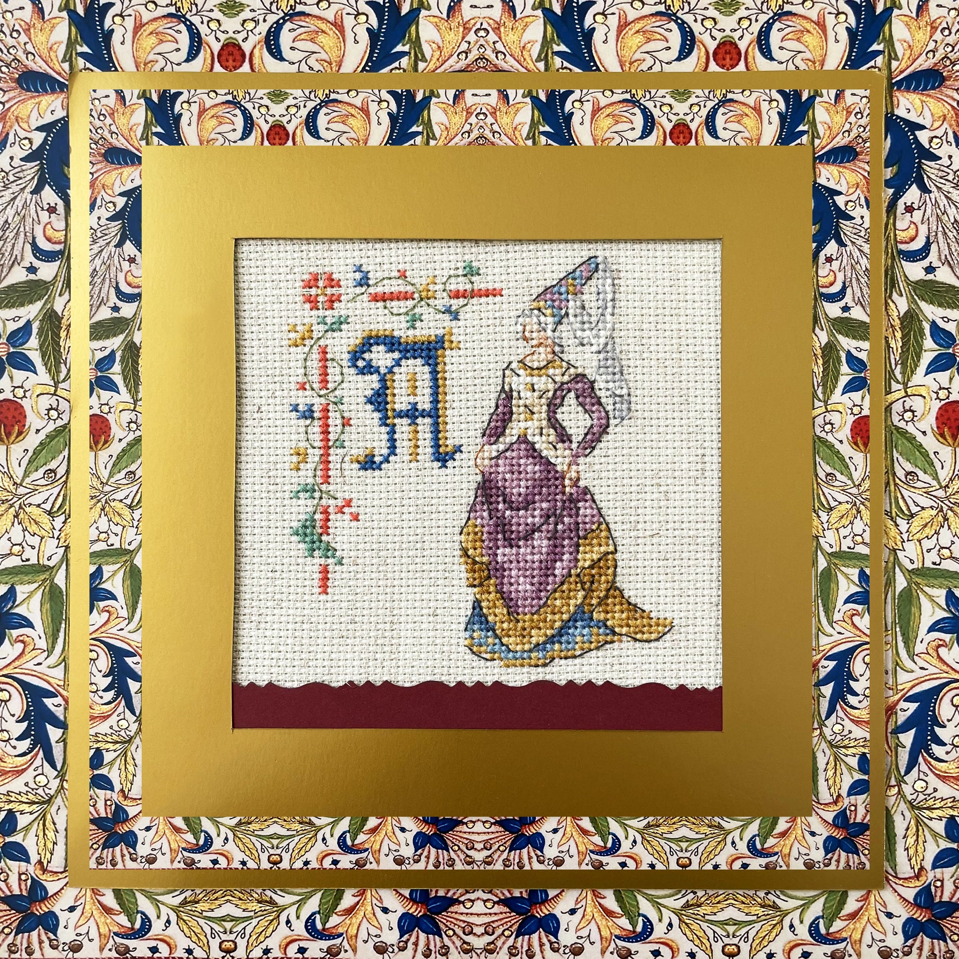 Grille point de croix : alphabet médiéval, damoiselles et motifs floraux. 52×52 pts, lin 11 fils/cm ou Aïda 5,5 pts/cm. 6 pages couleur, réf. DMC.
