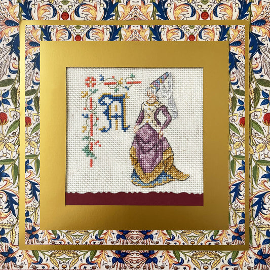 Grille point de croix : alphabet médiéval, damoiselles et motifs floraux. 52×52 pts, lin 11 fils/cm ou Aïda 5,5 pts/cm. 6 pages couleur, réf. DMC.