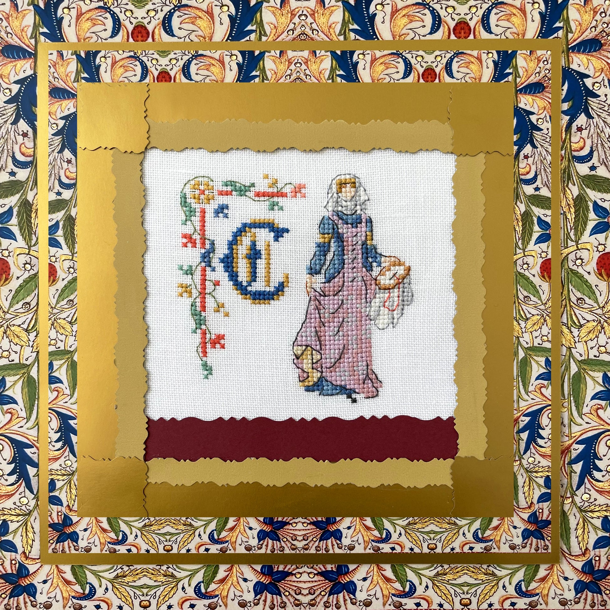 Grille point de croix : alphabet médiéval, damoiselles et motifs floraux. 52×52 pts, lin 11 fils/cm ou Aïda 5,5 pts/cm. 6 pages couleur, réf. DMC.