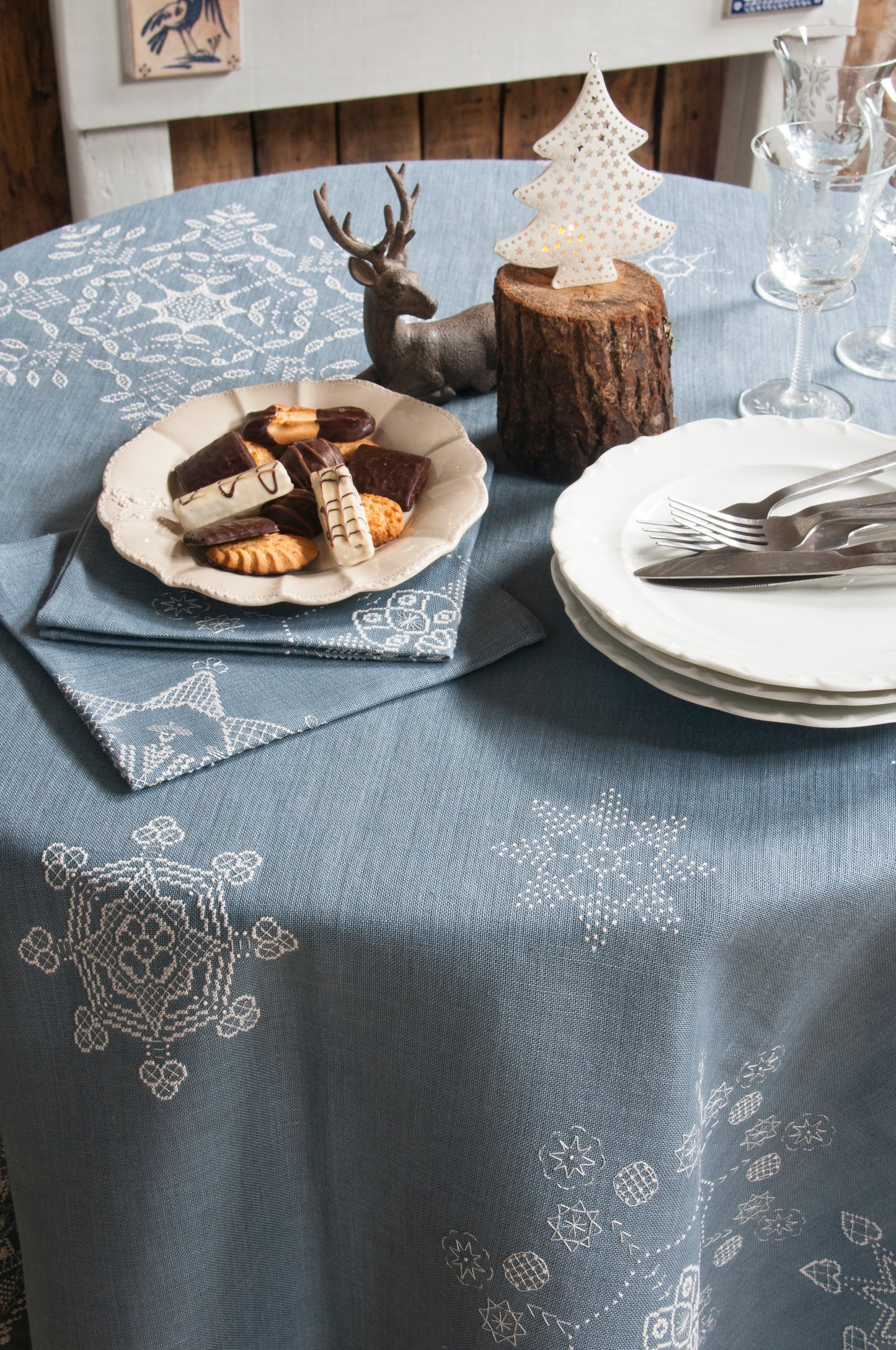 Grille de broderie point de croix « Flocons de Noël » : nappe et serviettes brodées de flocons sur toile de lin bleue. DMC, 10 pages – déco de table Noël.