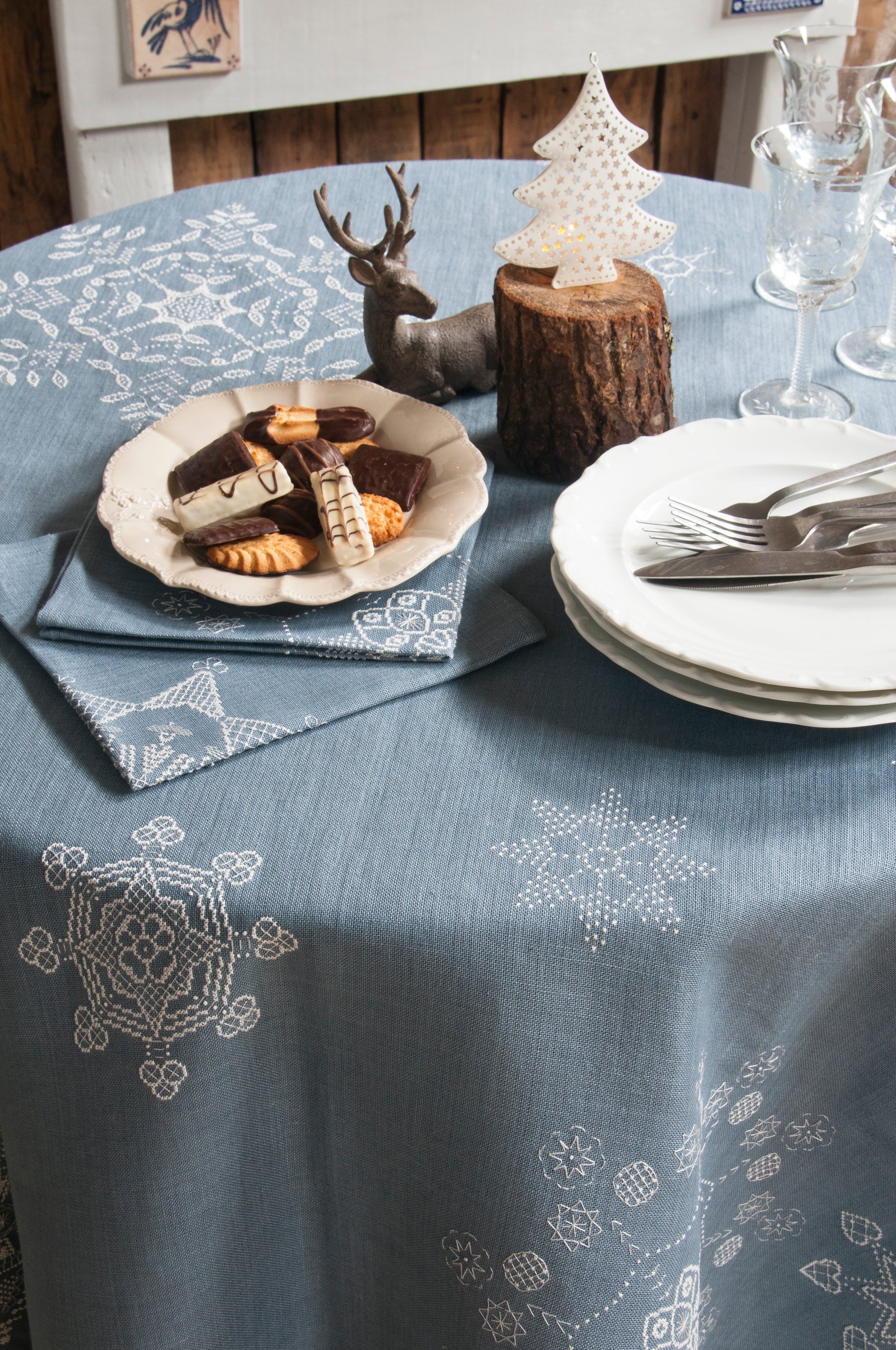 Grille de broderie point de croix « Flocons de Noël » : nappe et serviettes brodées de flocons sur toile de lin bleue. DMC, 10 pages – déco de table Noël.