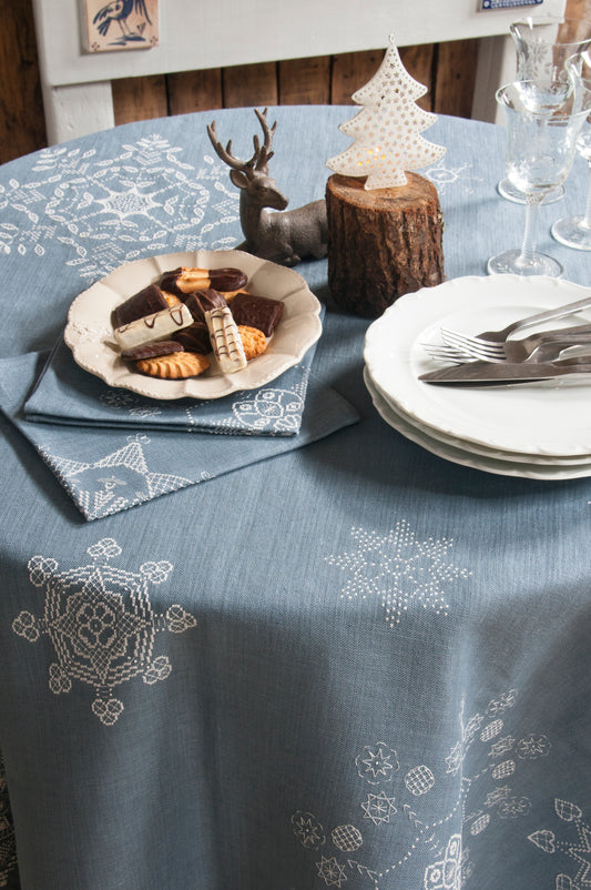 Grille de broderie point de croix « Flocons de Noël » : nappe et serviettes brodées de flocons sur toile de lin bleue. DMC, 10 pages – déco de table Noël.