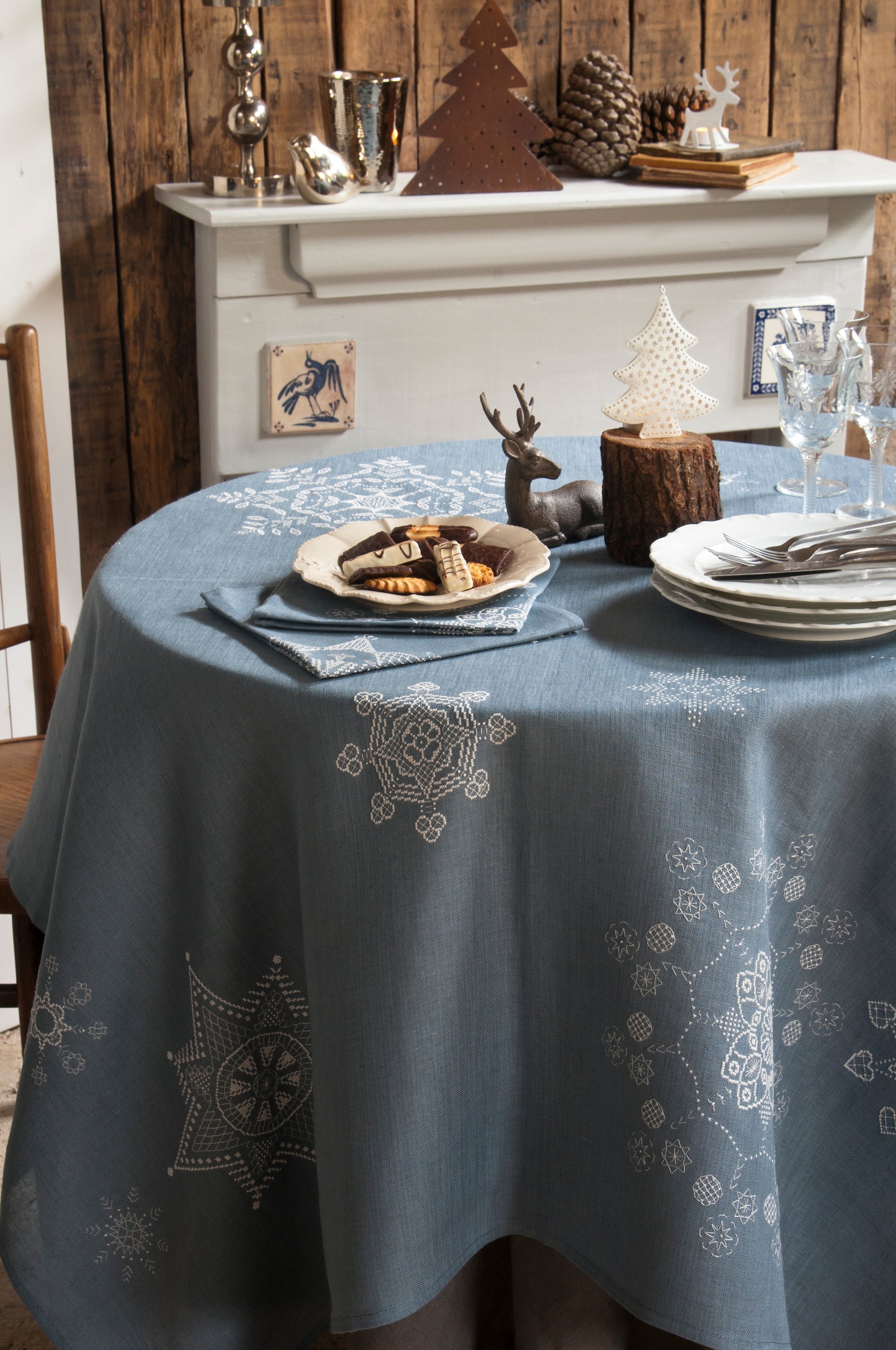 Grille de broderie point de croix « Flocons de Noël » : nappe et serviettes brodées de flocons sur toile de lin bleue. DMC, 10 pages – déco de table Noël.