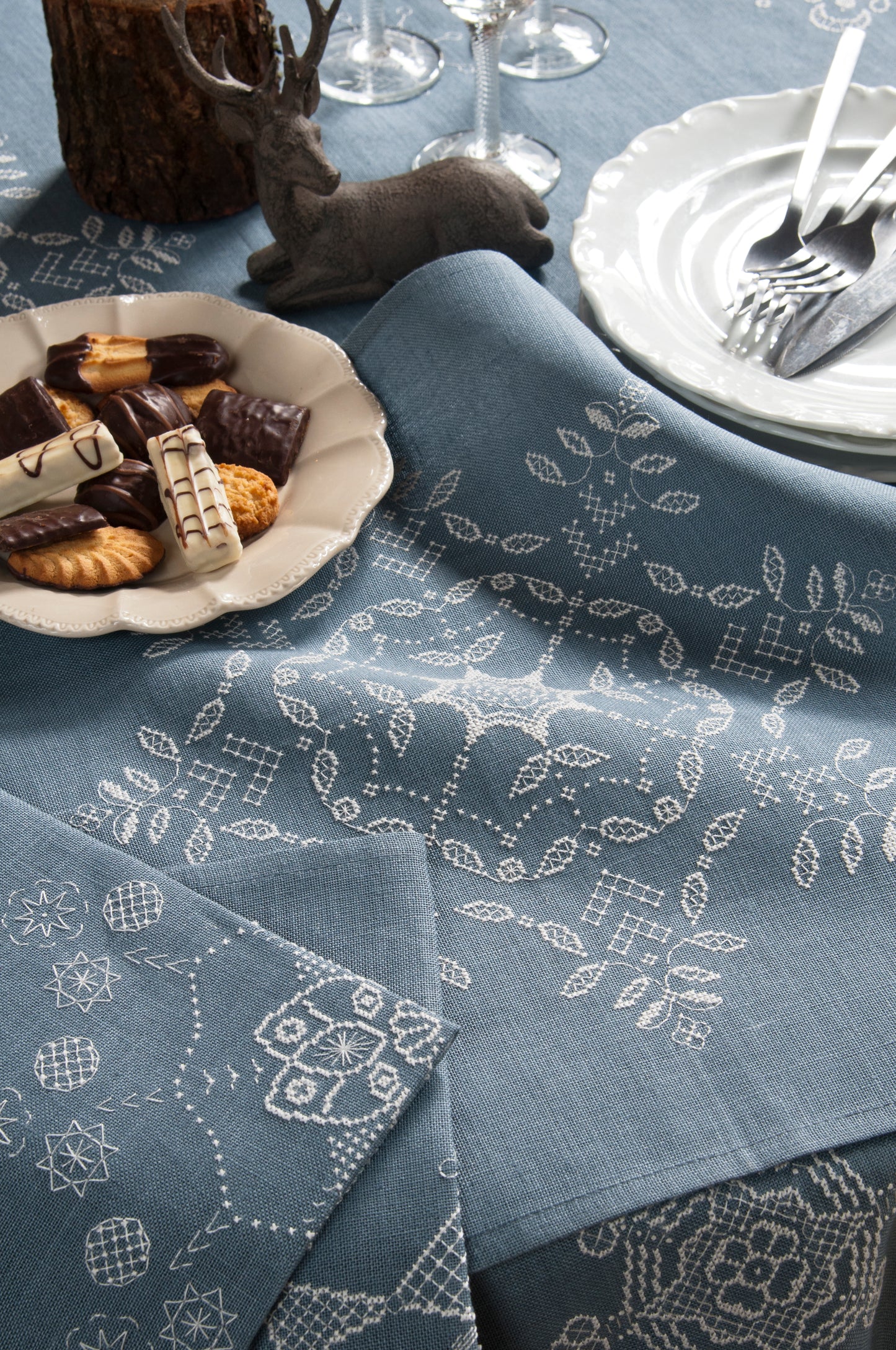 Grille de broderie point de croix « Flocons de Noël » : nappe et serviettes brodées de flocons sur toile de lin bleue. DMC, 10 pages – déco de table Noël.