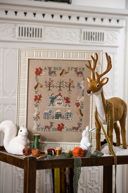 Grille de point de croix L'Hiver Enchanté – abécédaire hivernal avec écureuils, cerfs, lapins et enfants patinant, brodé sur lin naturel 11 fils/cm, Création Point de Croix