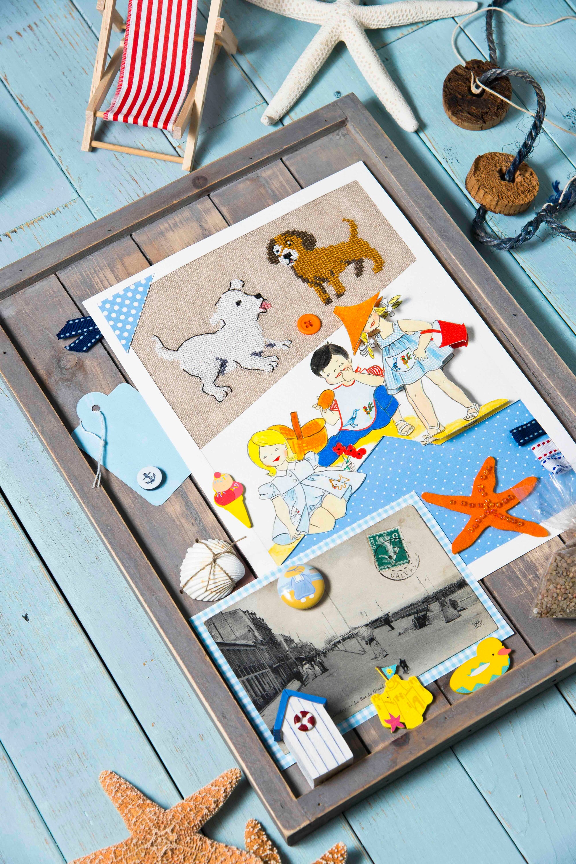 Grille point de croix – La plage, mise en scène : composition créative broderie et papiers décoratifs avec cabines de plage colorées et souvenirs de vacances – Création Point de Croix