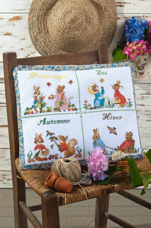Grille point de croix : coussin 4 saisons Pierrot-Lapin sur lin blanc DMC. Motif 197 × 157 pts, env. 35,8 × 28,5 cm. Imprimé symboles & couleurs, 6 pages.