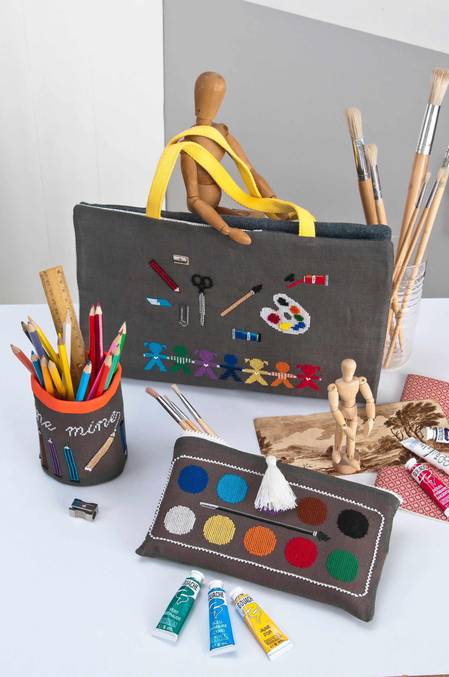 Grille broderie point de croix : valise, trousse et pot à crayons. 8 pages, symboles et couleurs DMC. Lin flanelle 12 fils.