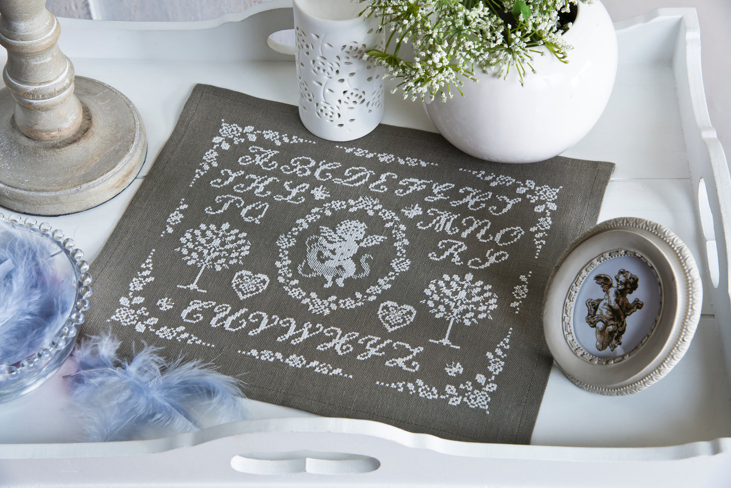 Grand sampler monochrome blanc sur lin gris : angelot, abécédaire, arbres de vie et cœurs brodés. Esprit marquoir ancien, 29 × 23,6 cm.
