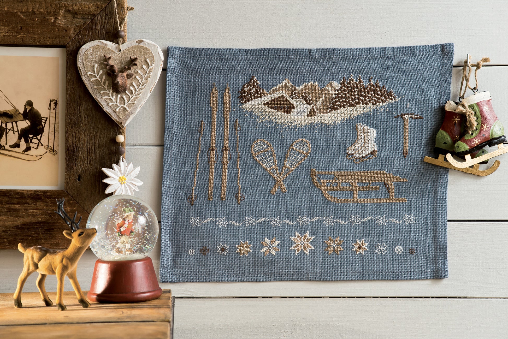 Grille point de croix : accessoires de sports d'hiver vintage sur lin bleu ardoise. Motif 160×130 pts, environ 29,1×23,6 cm. Esprit rétro montagne.