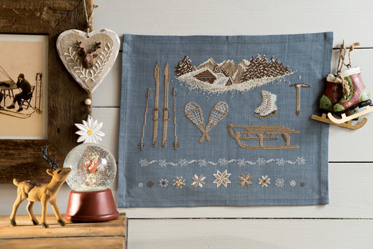 Grille point de croix : accessoires de sports d'hiver vintage sur lin bleu ardoise. Motif 160×130 pts, environ 29,1×23,6 cm. Esprit rétro montagne.